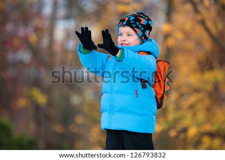Adorable little boy having fun in autumn park