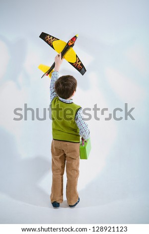 Little boy holding a plane model to aim his target let the plane fly high to the sky