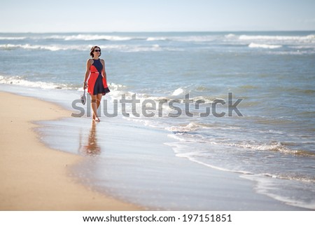 Young woman walking along a beach on beautiful summer day
