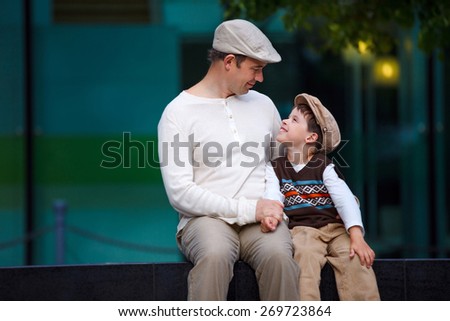 Happy father and son talking and having rest outdoors in city on beautiful summer day