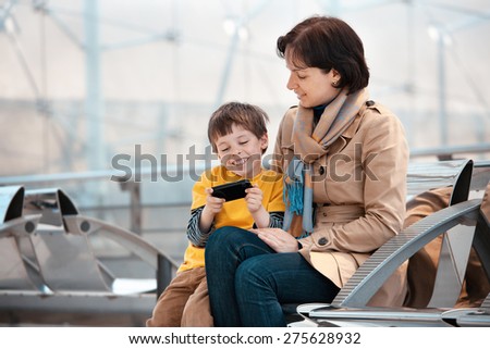 Loving mother and son using smartphone at airport, going on holiday