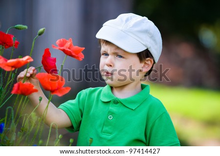 Cute three years old boy smells a wild flower