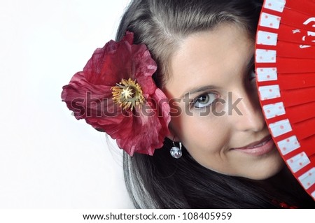 Face of spanish girl with fan and flower in her hair close up.