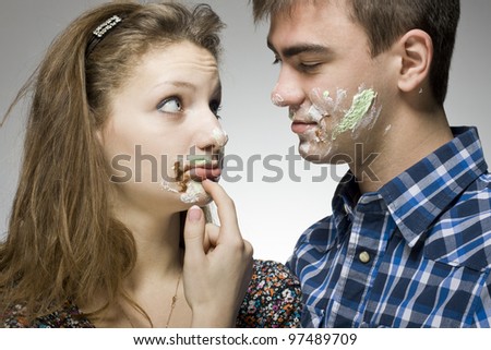 Young couple with cake on face.