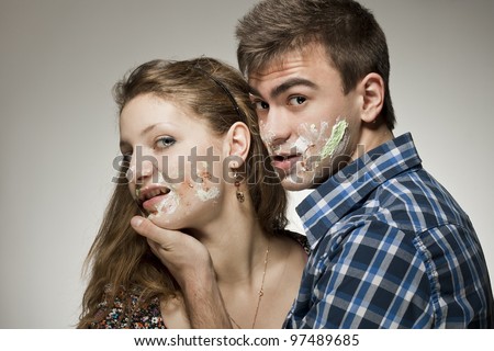 Young couple with cake on face.