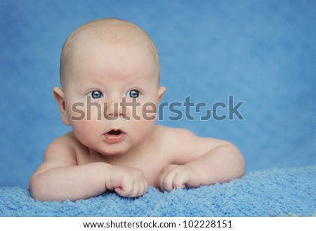 Curious, happy, three months old baby posing on blue blanket.