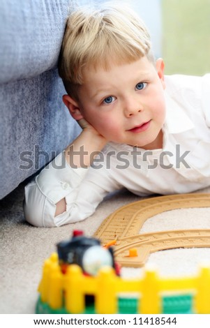 Happy five year old boy playing with his train set