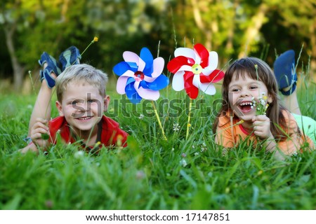 Five year old friends laying in a grass with colorful pinwheels