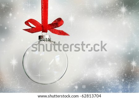 Transparent Christmas ball hanging on red ribbon on snowy winter background