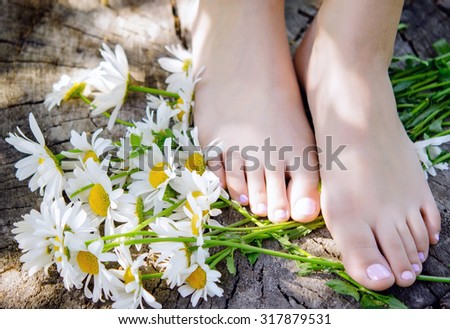 close up of woman feet with camomiles
