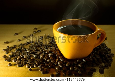 smoking hot coffee with coffee beans on wooden table