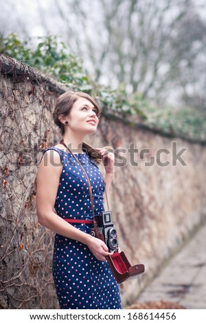 Beautiful young woman taking pictures with a vintage camera