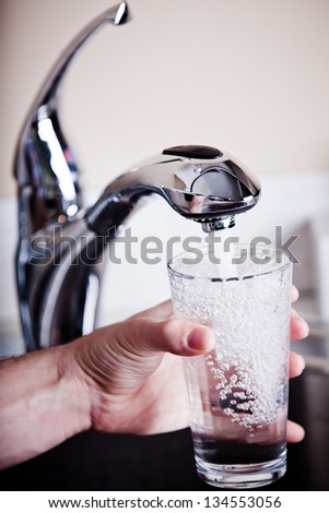 Thirsty man filling a glass of water