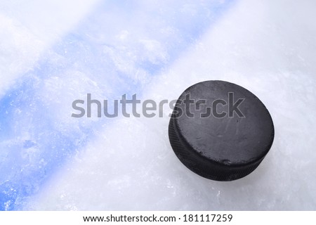 Vintage old hockey puck is on the ice near the blue line