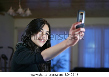 Young teen girl taking own pictures on camera phone