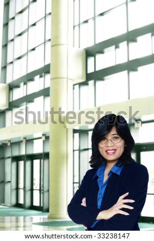 Asian business woman with arms crossed in large office complex