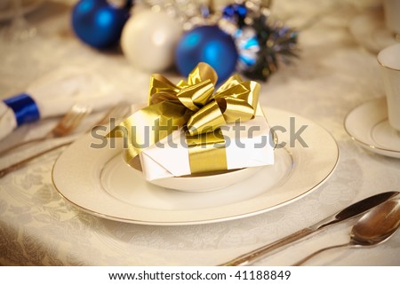 Elegant blue and white Christmas table setting with gold ribbon gift