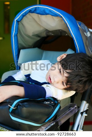 Disabled five year old boy in wheelchair at school, looking tired