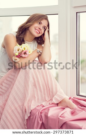 Stylish woman with flowers sitting by the window