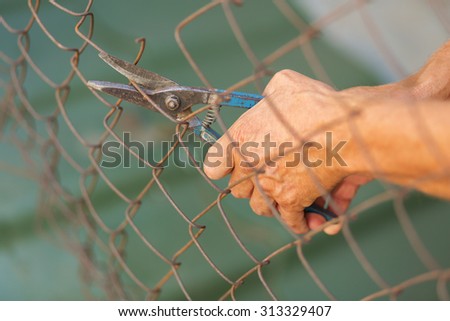 A man breaking down the fence with cutter. Immigration concept