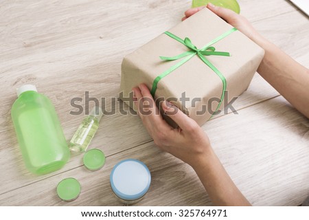 Gift box with green ribbon and cosmetics on a wooden background