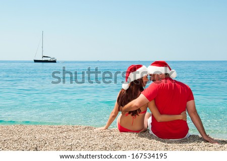 Christmas holidays by the sea. Girl with a guy wearing santa claus.