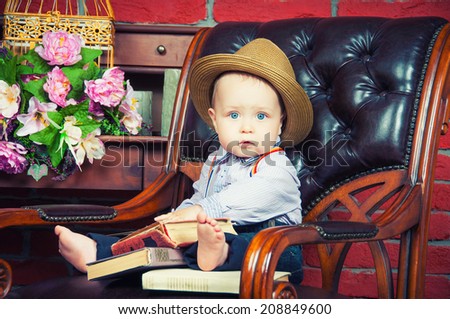 Little boss. Baby gentleman sitting in a leather chair in the hat