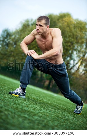 Young muscular  man doing stretching exercise for the legs