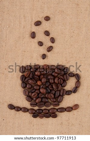 A cup of coffee beans with smoke on the background of burlap.
