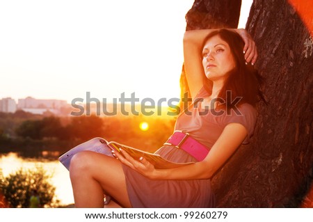 The girl with the magazine wants to sit at sunset.
