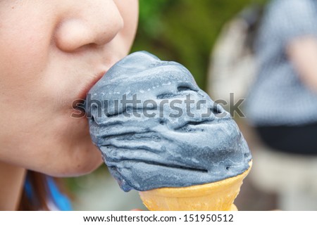 Girl eating black ice cream, valley Ashi, Japan.