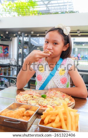 Asian girl child eat pizza in a restaurant