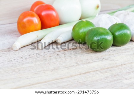 Thailand herb ingredients: lemon grass, lime, lemon, tomato, onion and garlic on wood table.