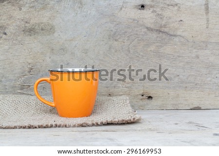 Coffee cup of orange put on a hemp cloth on wood background on a wooden.