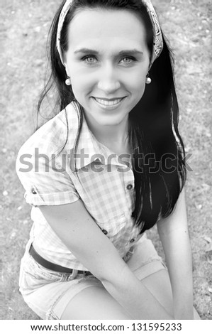 Black and white outdoor portrait of a beautiful, brunette vintage, retro, smiling pin up girl.