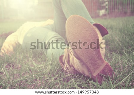Woman lying on a grass relaxing with jeans and traveling shoes, close-up on her soles,