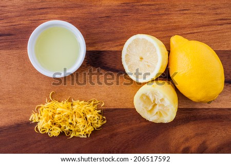 Baking ingredients for a lemon cake - lemon rind, squeezed lemon, lemon juice and lemon zester on a wooden background