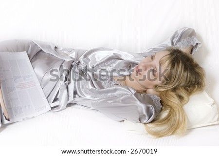 A women in a silver silk robe dreaming on the sofa