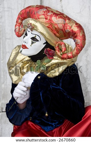 A clown with a red hat, gold collar and a rose