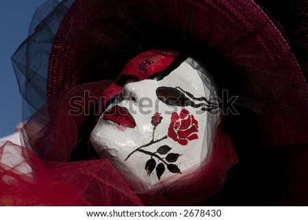 A rose painted on a red and white venetian mask