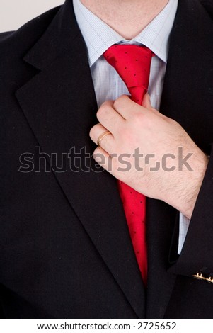 A business man in a blue suit, straightening his red tie