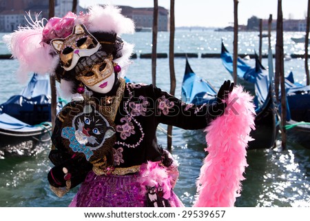 Lady with cat masks in a pink and black costume at the Venice Carnival