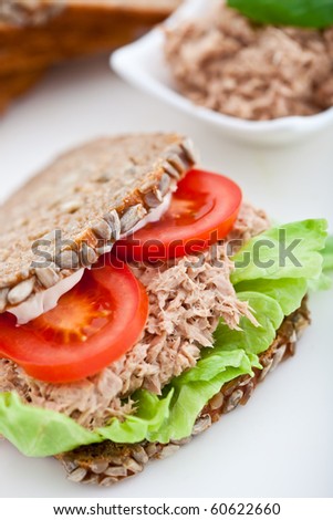 Tuna fish sandwich with tomatoes, lettuce and mayonnaise on a wooden board. Shallow DOF