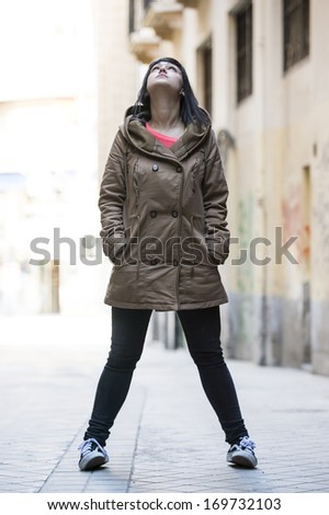 Young modern woman looking up, with a coat.