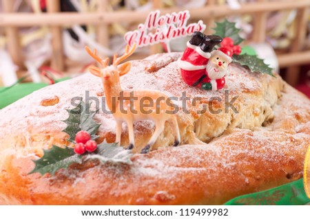 Santa and a reindeer on a Christmas stollen with a hamper at the background