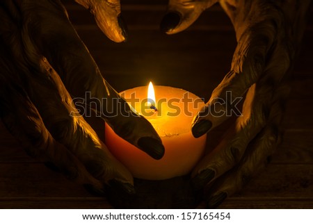 The werewolf hands and a burning candle close up