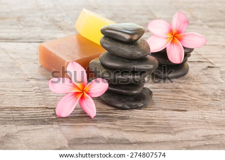 Plumeria flower, soaps and black stones on wooden background