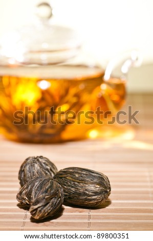 Dry blooming tea closeup with glass teapot at background