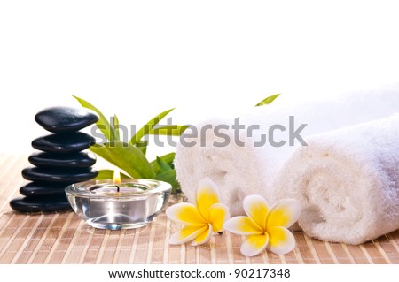Spa concept with black zen stones, flowers on bamboo mat background
