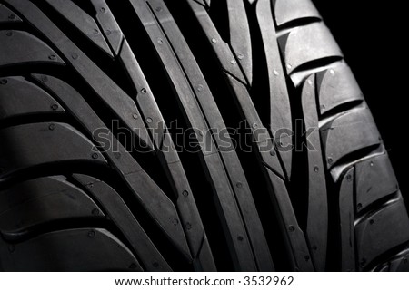 Summer tire (225/45R17) on black background. It\'s a new one. Close-Up.